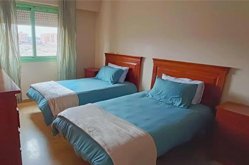 a bedroom with two beds with blue sheets and a window at Apartamento en Majorelle, Marrakech. in Marrakesh