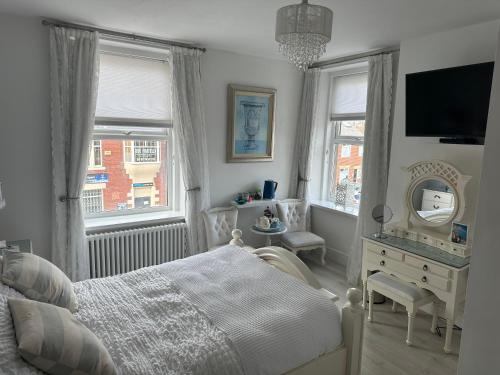 a bedroom with a bed and a dresser and a mirror at Coastal Joy - Room 5 in Newbiggin-by-the-Sea