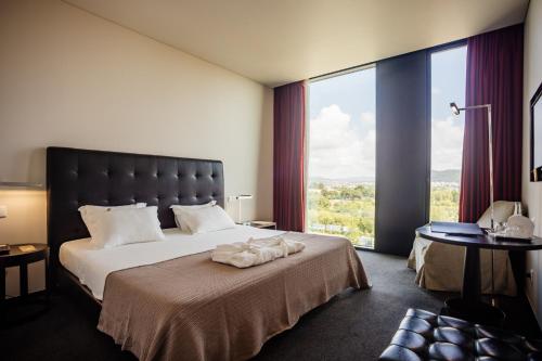 a bedroom with a large bed with a large window at Axis Viana Business & SPA Hotel in Viana do Castelo