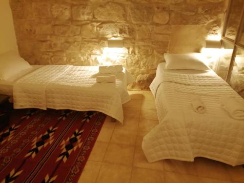 1 dormitorio con 2 camas y pared de piedra en Dana Gardens Hotel, en Dana