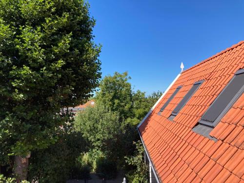 an orange roof on top of a house with trees at het zwaluwnest in Koudekerke
