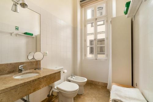 a bathroom with a toilet and a sink and a window at Alcácer Flat in Alcácer do Sal