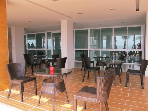 a dining room with tables and chairs and windows at Nantra Pattaya Baan Ampoe Beach in Na Jomtien