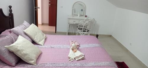 uma boneca está deitada numa cama rosa em La maison du bonheur em Celavisa