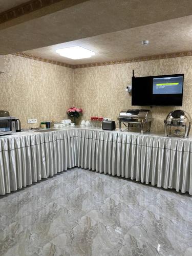 un vestíbulo con una mesa larga con una pantalla en la pared en Caravan Castle Boutique Hotel, en Bukhara