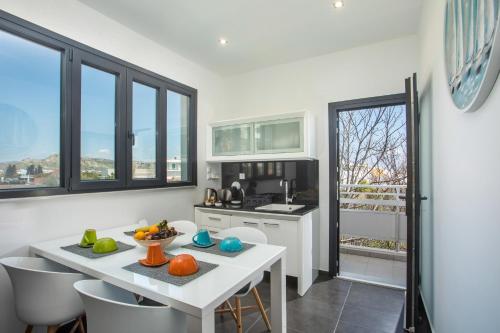 a kitchen with a white table and chairs and windows at Faliro Hotel in Faliraki