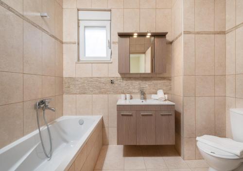 a bathroom with a tub and a sink and a toilet at Nik-Ntin Villa Deluxe in Prinos