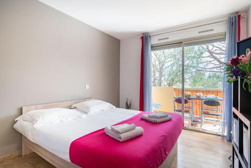 ein Schlafzimmer mit einem großen Bett mit einer rosa Decke in der Unterkunft Spacieux 2pièces à5min de plages in Antibes