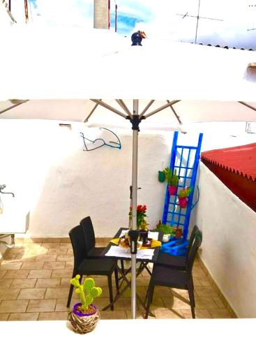 a patio with a table and chairs and an umbrella at Antiche Mura Apartments "Nel Cuore della Puglia"bivani, cucina, terrazzo in Turi