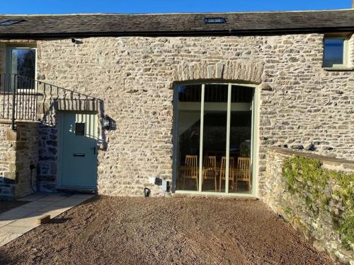 a stone house with a blue door and a patio at The Old Shippon, Barbon in Barbon