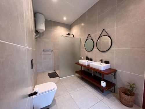 a bathroom with a toilet and two sinks and a shower at Villa 4 Chambres avec piscine sur Kribi in Kribi