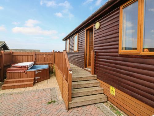 a wooden house with a deck and a hot tub at Seascape Retreat in Ilfracombe