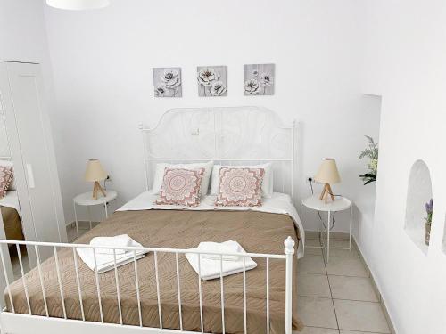 een slaapkamer met een bed met roze kussens en 2 tafels bij Kampos View - Quiet House at the end of the Road, private pool in Kámbos