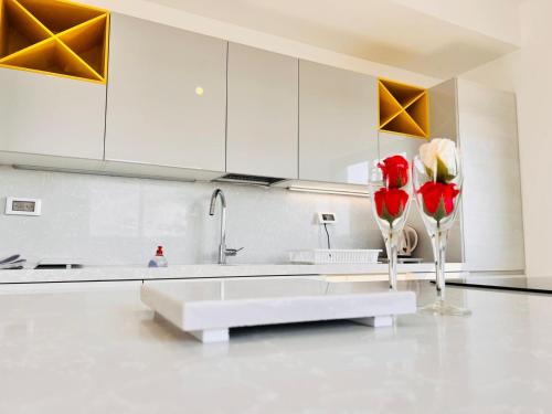 Luxury Penthouse 5 Rooms في Or Yehuda: مطبخ مع ورود حمراء في مزهرية على المنضدة