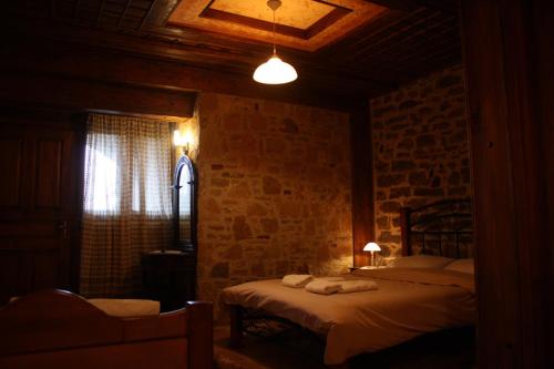 a bedroom with two beds and a stone wall at Guesthouse To Spiti Τou Gakou in Nestórion