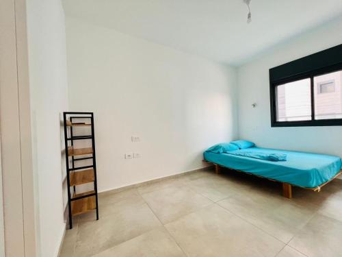 a small room with a blue bed and a ladder at Luxury Penthouse 5 Rooms in Or Yehuda