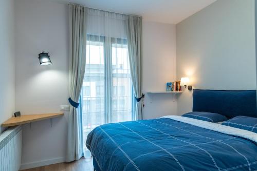 ein Schlafzimmer mit einem blauen Bett und einem großen Fenster in der Unterkunft Sofia Apartment with Free Parking in Sofia
