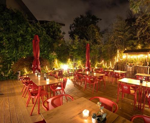 un restaurante con mesas de madera, sillas rojas y luces en Hostel & cia, en Oporto