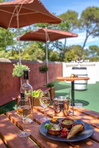 a wooden table with two glasses of wine and food at Les Pins Blancs en Provence in Le Muy