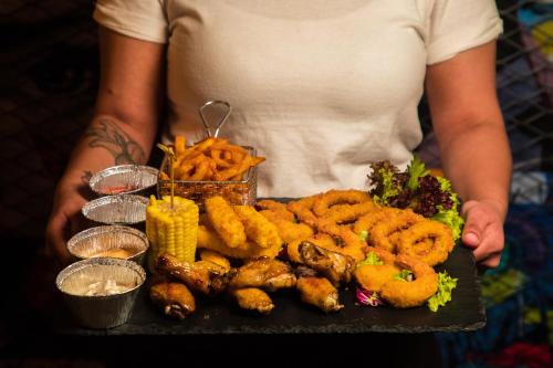 a person holding a tray of food with onion rings and other foods at Elite Byblos Hotel in Dubai