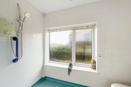 ein Bad mit einer Dusche, einem Fenster und einer Badewanne in der Unterkunft Beautiful Boutique Derbyshire Abode - Games room in Derby