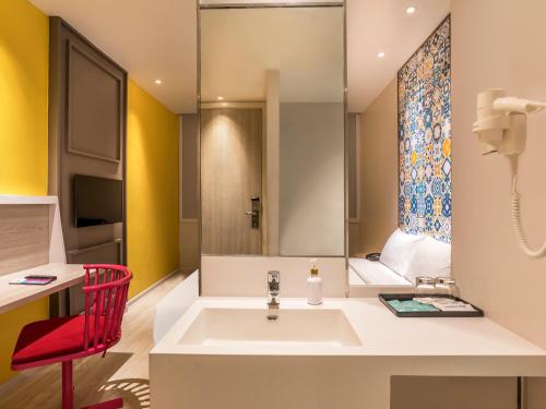 a bathroom with a sink and a red chair at Ibis Styles Phuket City in Phuket Town