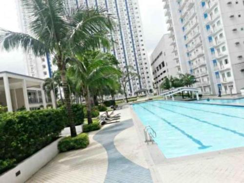 a swimming pool with palm trees and buildings at Grass Residences by Team A in Manila