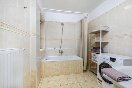 a bathroom with a tub and a washing machine at Venus Apartments - Opera II in Budapest