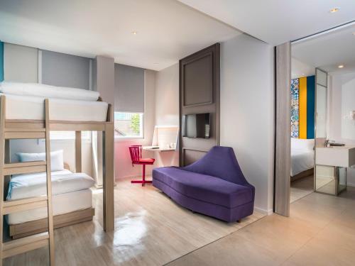 a bedroom with two bunk beds and a purple chair at Ibis Styles Phuket City in Phuket