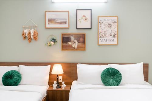 two beds in a hotel room with pictures on the wall at SAZI BEN THANH Hotel HCM in Ho Chi Minh City
