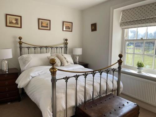 a bedroom with a bed with white sheets and a window at Station House, Gilling in Gilling East