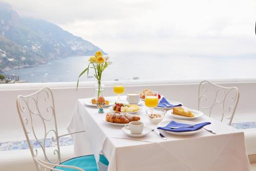 un tavolo con cibo sopra con vista sull'oceano di Hotel Conca d'Oro a Positano