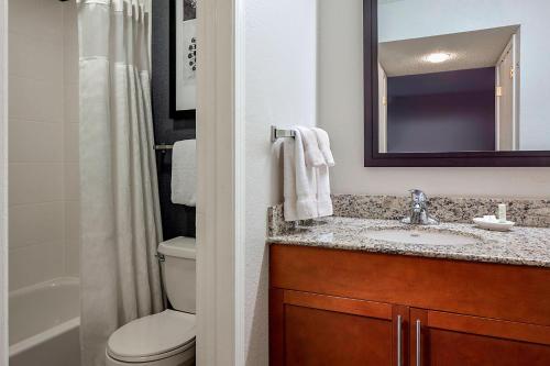 a bathroom with a sink and a toilet and a mirror at Residence Inn Dallas Las Colinas in Irving