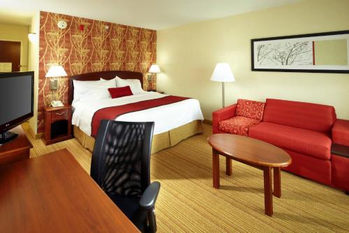 a hotel room with a bed and a red couch at Courtyard Newark Granville in Newark