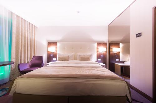 a bedroom with a large bed and a purple chair at Hotel Transilvania in Alba Iulia