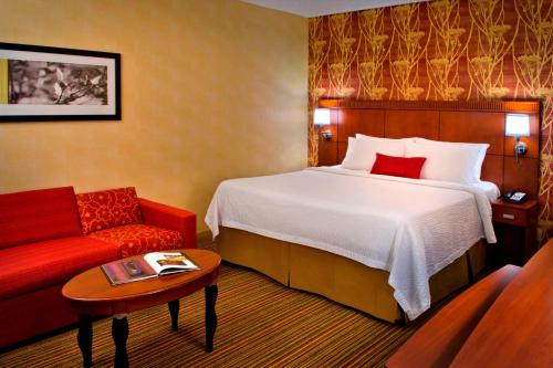 a hotel room with a bed and a red couch at Courtyard by Marriott Mt. Laurel in Mount Laurel