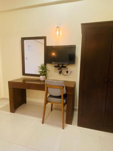 a desk with a computer and a mirror and a chair at Hotel NorthWay in Vavuniya