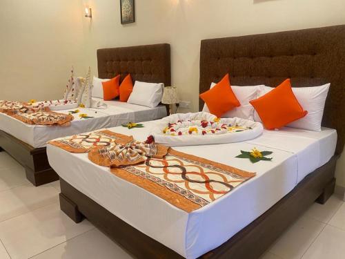 two beds in a room with orange and white at Hotel NorthWay in Vavuniya