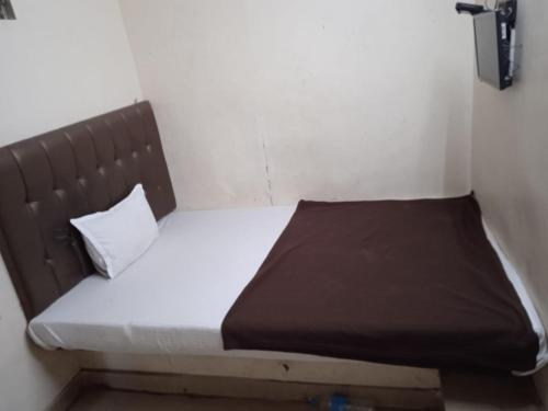 a small bed in a small room with a brown headboard at Hotel janata Residency in Mumbai