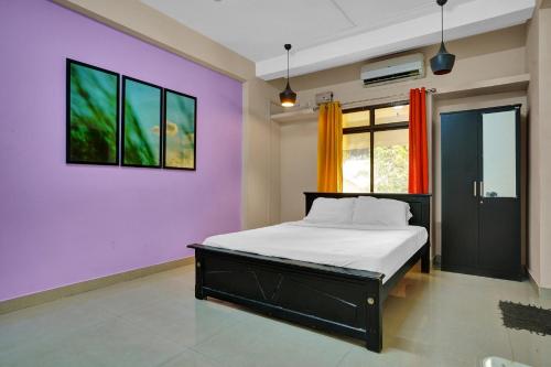 a bedroom with a bed and a purple wall at Collection O Lala Homes in Cochin