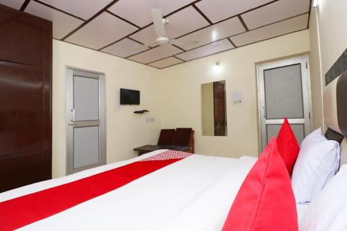 a bedroom with a large white bed with red pillows at Hotel O Country Lodge in Dharamshala