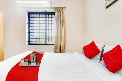 a bedroom with a bed with red pillows and a window at OYO The Safe Hotels in Cochin