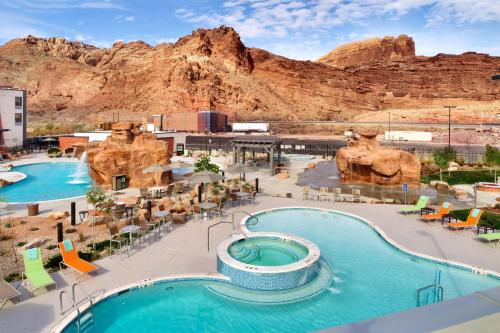 a resort with two pools and chairs and a mountain at SpringHill Suites by Marriott Moab in Moab