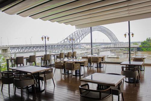 a restaurant with tables and chairs and a view of a bridge at HARRIS Hotel Samarinda in Samarinda