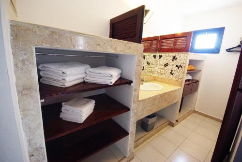 a bathroom with a sink and towels on a shelf at Caribbean Village Agador - All inclusive in Agadir