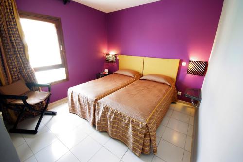 a bedroom with a bed and a purple wall at Caribbean Village Agador - All inclusive in Agadir