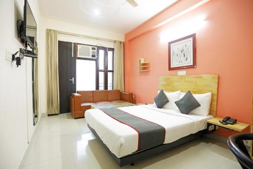 a bedroom with a bed with orange walls and a couch at Townhouse Cloud Bay, Near Genpact, Sector-69, Gurgaon in Gurgaon