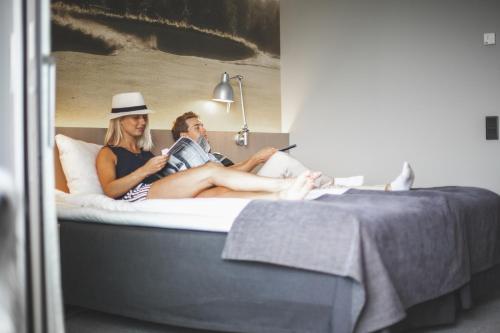 a man and woman sitting on a bed at Ringenäs Hotell & Konferens in Halmstad