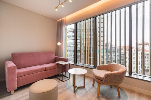 a living room with a couch and a large window at LUSTER Hotel in Lisbon