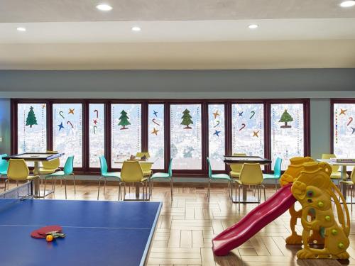 a playroom with a slide and tables and windows at Club Mahindra Snow Peaks Manali in Manāli